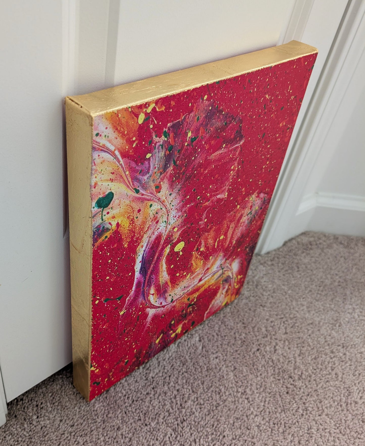 Side angle of the red abstract fluid art canvas showing the hand-applied gold leaf covering the edges, highlighting the contrast between the metallic sides and the vibrant painted front.