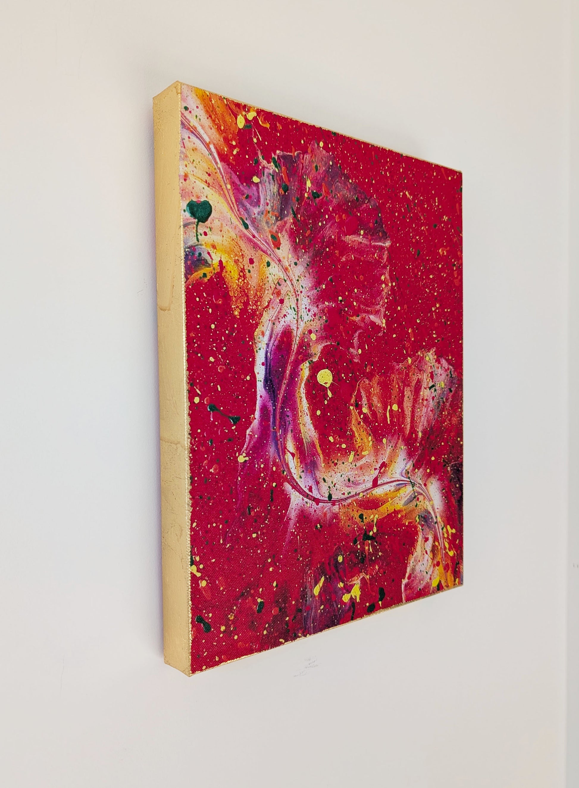 The gold-leafed edge of the canvas displayed against a white wall, showing how the metallic finish wraps around the side of the vibrant red fluid art print