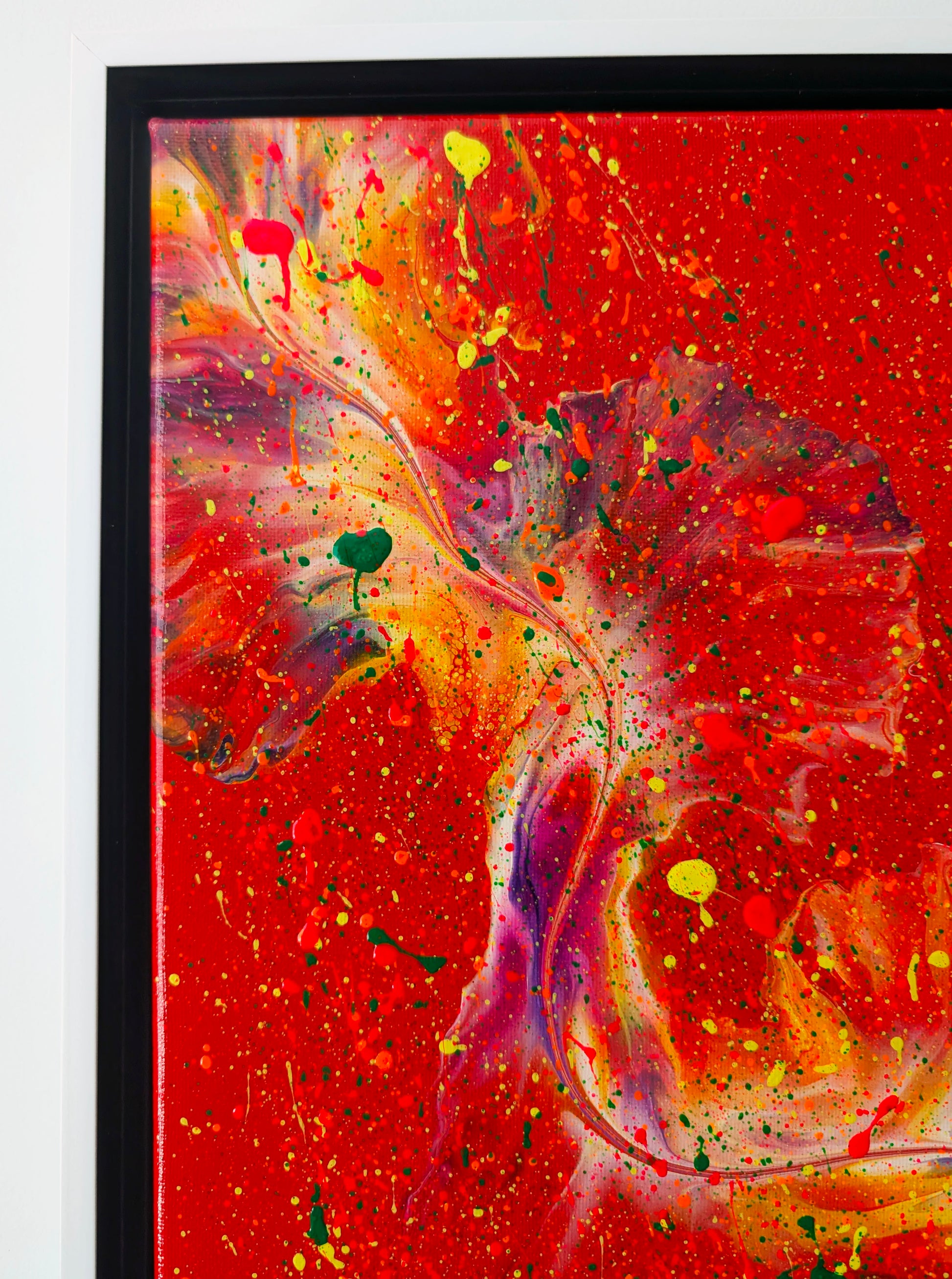 Close-up of the upper left area of the painting showing textured splashes of red, orange, and green paint on a fiery red base with subtle purple highlights.