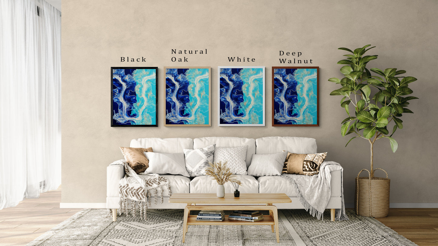 Four framed prints of Abby May Art’s “The Fine Line” painting displayed above a cream sofa. The artwork features flowing deep navy, turquoise, and white fluid patterns reminiscent of ocean waves. Frame colors—Black, Natural Oak, White, and Deep Walnut—are shown side by side with labels to compare how each frame complements the artwork in a living room setting.