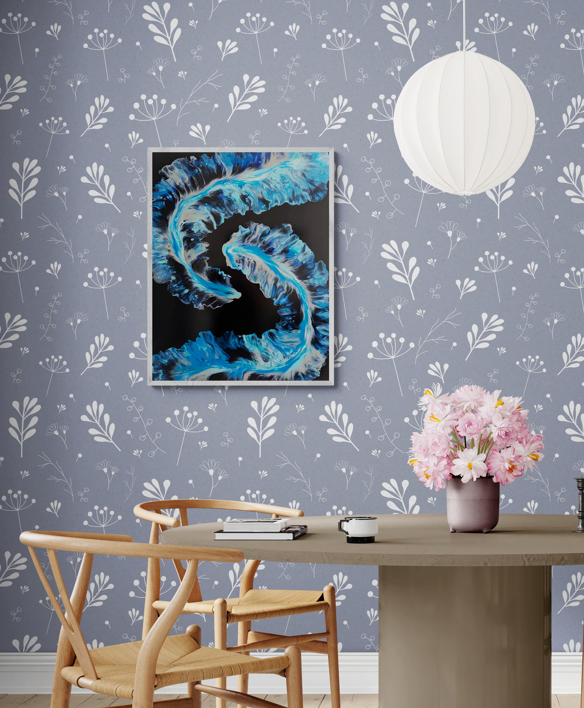 Framed painting titled “Tidal” displayed above a round table with flowers, styled on a soft periwinkle wallpaper with white floral patterns. The artwork features flowing blues, whites, and deep blue tones that resemble ocean waves.