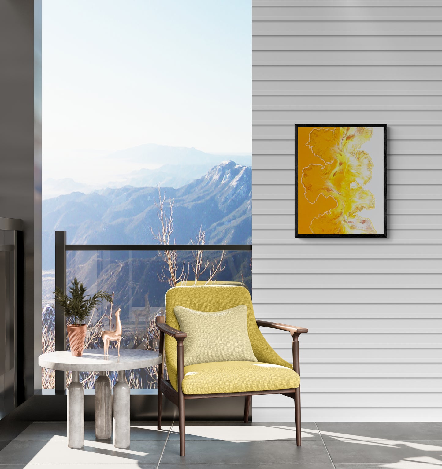 A bold abstract painting titled "Walk the Line" is framed in black and mounted on a white horizontal plank wall of a sunlit balcony. The artwork features fluid golden yellow and white forms with a strong vertical divide between an orange and white background. Below, a modern yellow accent chair with a cream pillow is paired with a concrete-legged side table holding a terracotta planter and decorative giraffe, set against a glass railing overlooking a breathtaking mountain view.