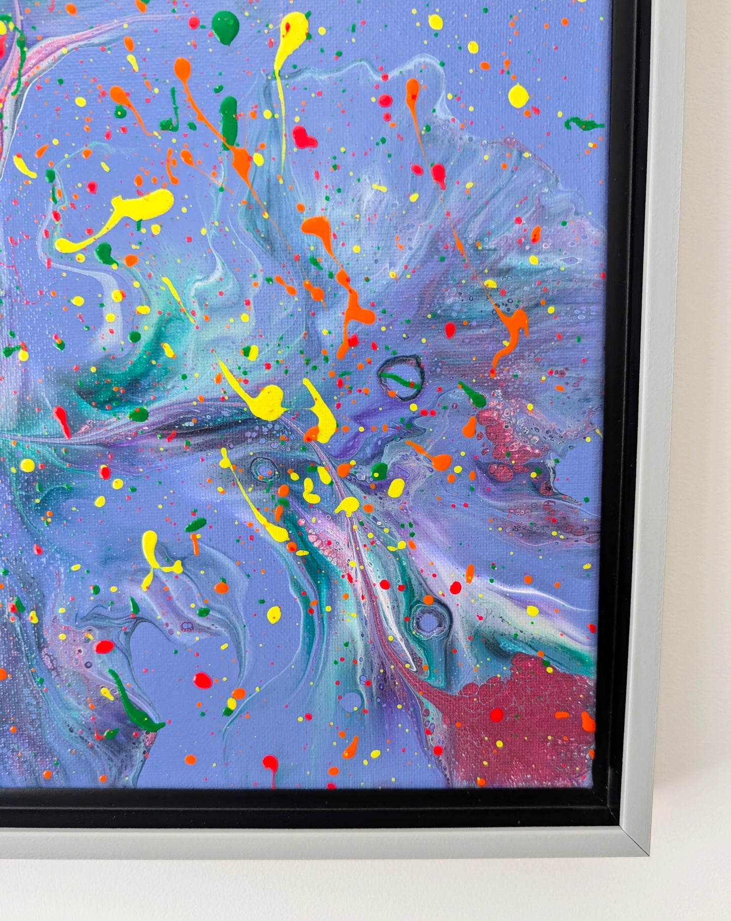Close-up of the bottom right corner of the painting, featuring swirling layers of purple, pink, and green. Neon splatters of orange, yellow, and red are scattered across the canvas, along with subtle cell-like textures.