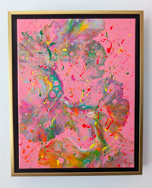 Framed acrylic fluid art painting with a vivid pink background. Flowing marbled textures in green, orange, yellow, and purple sweep across the canvas, overlaid with energetic neon splatters in red, yellow, and green