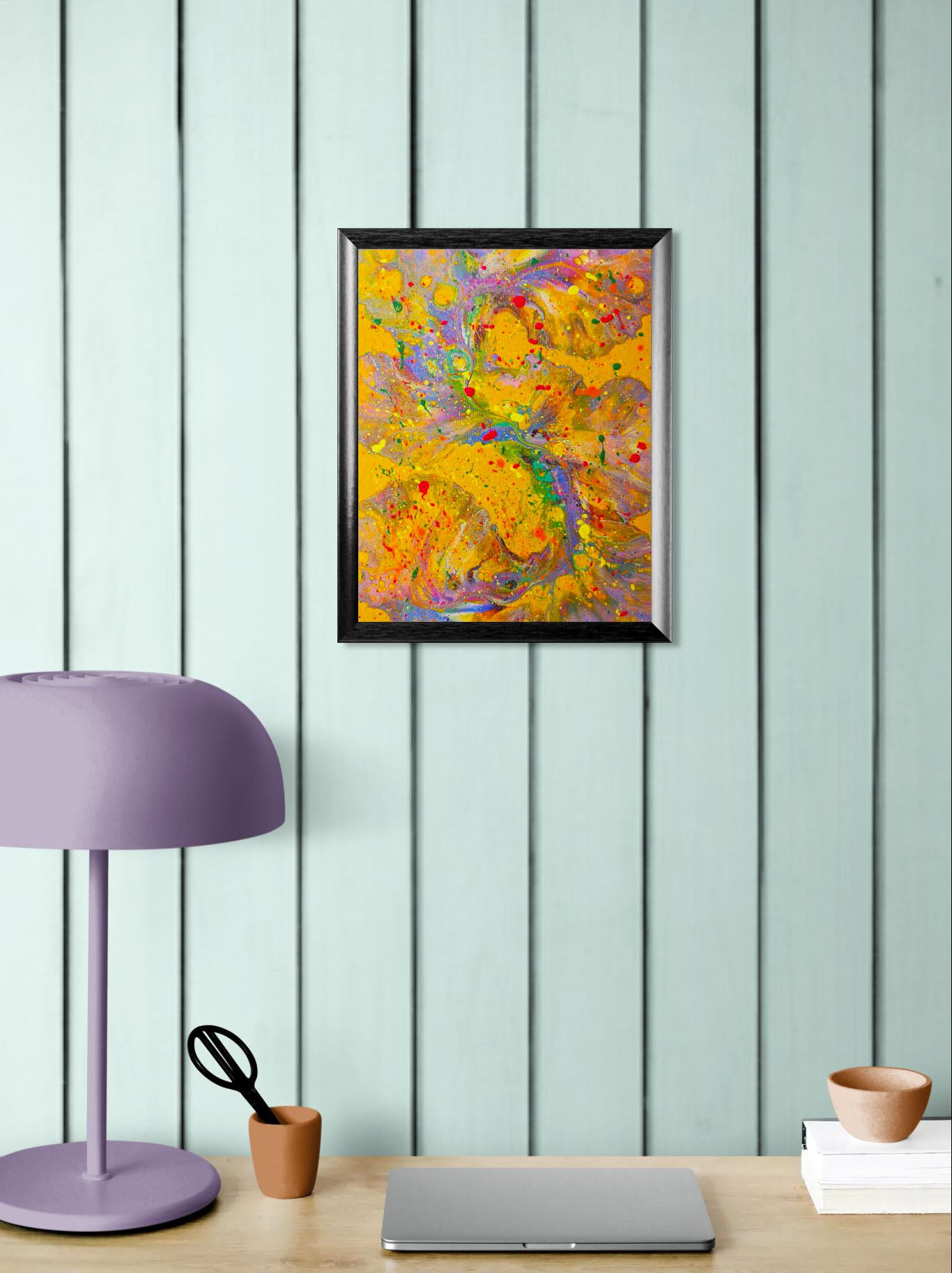 Mockup of the painting hanging on a wood-paneled wall above a desk setup with a lavender lamp, small terracotta cup, and a closed laptop. The vibrant artwork adds an expressive focal point to the workspace.