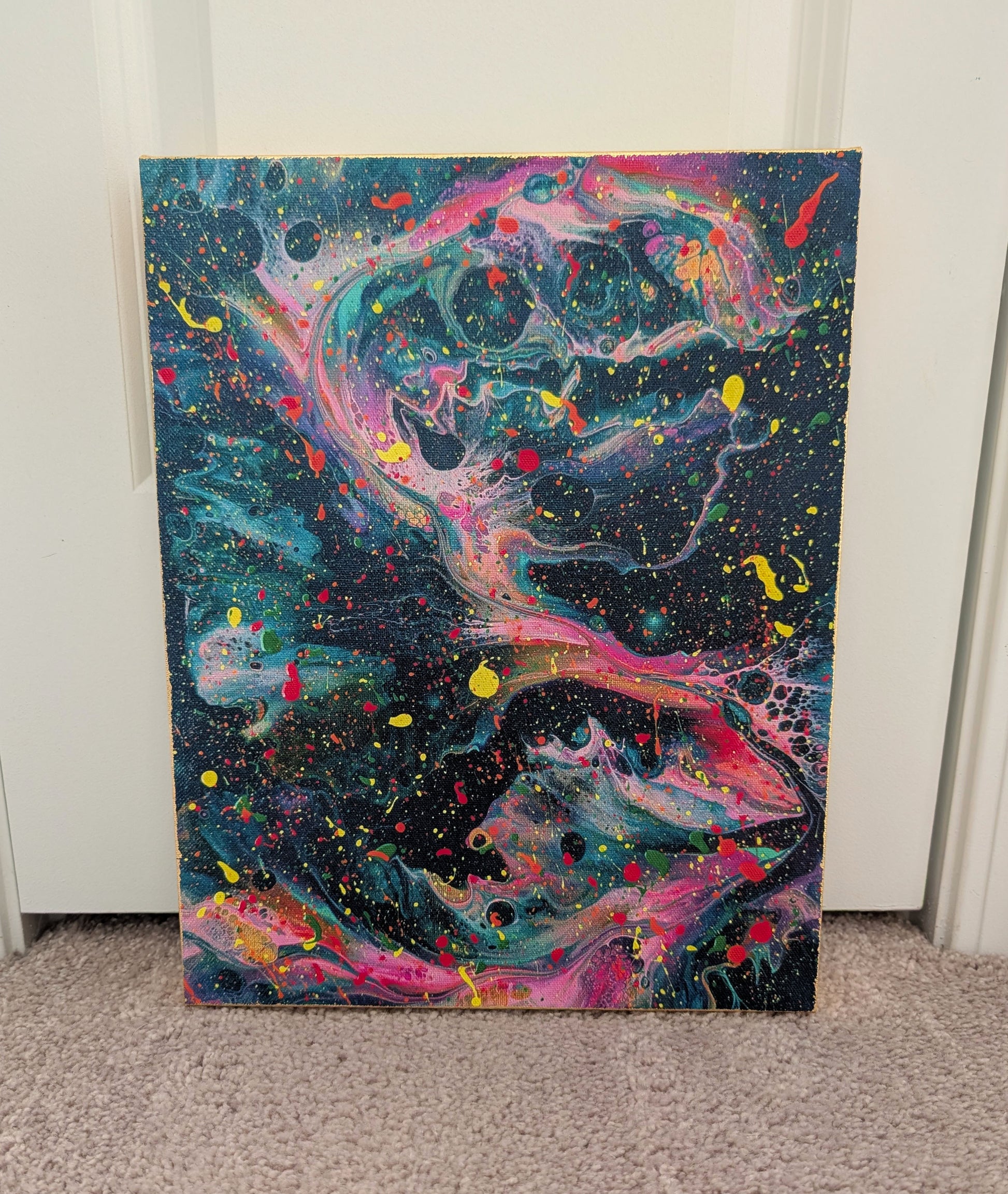 Front view of an abstract dark fluid art canvas with swirling teal, pink, purple, and yellow tones, layered with colorful paint splatters. The canvas edges are finished with gold leaf.