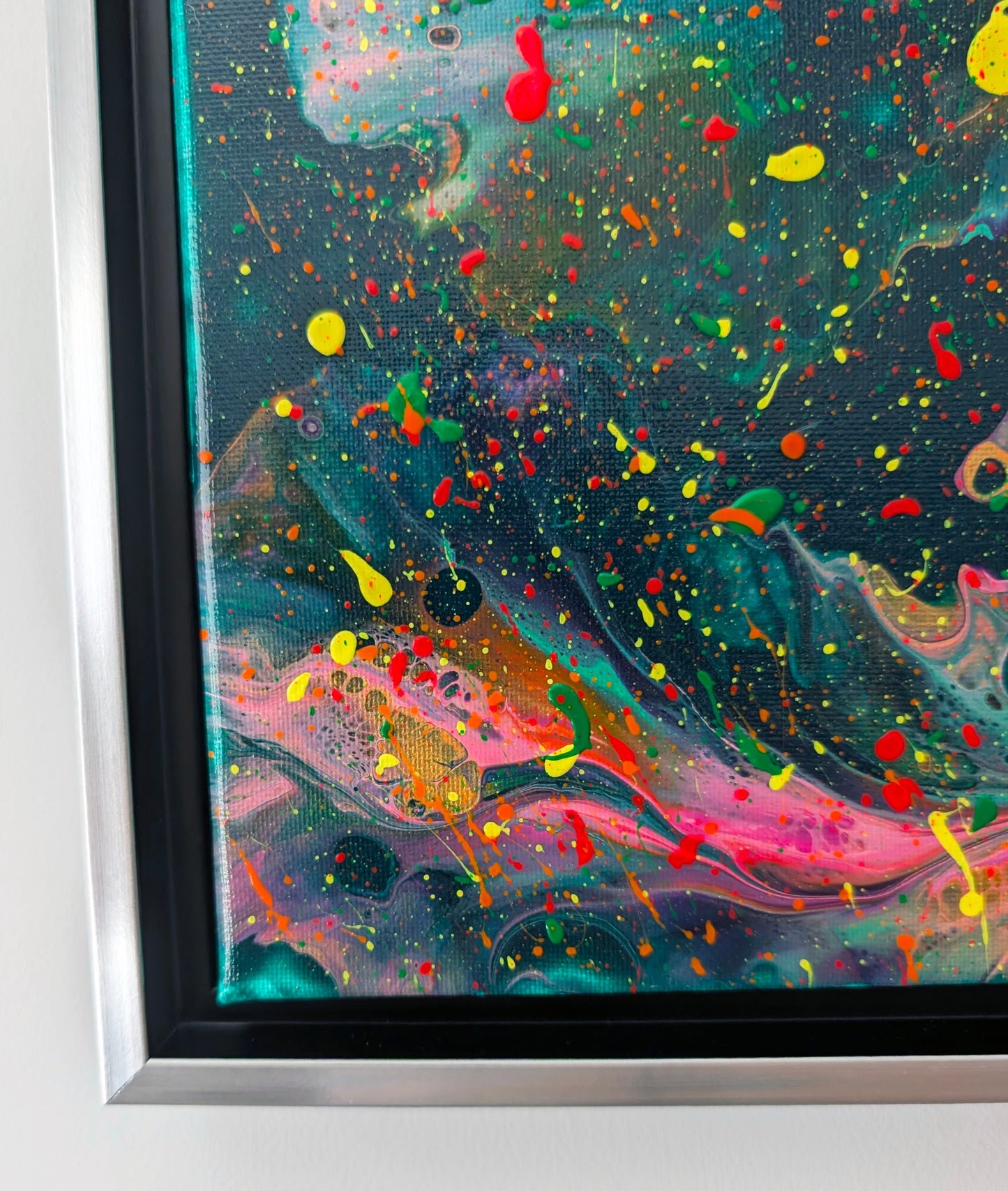 Detailed view of the bottom left corner, showing fluid paint textures in vibrant pink, yellow, and green with bubble-like cell patterns emerging through the colors.