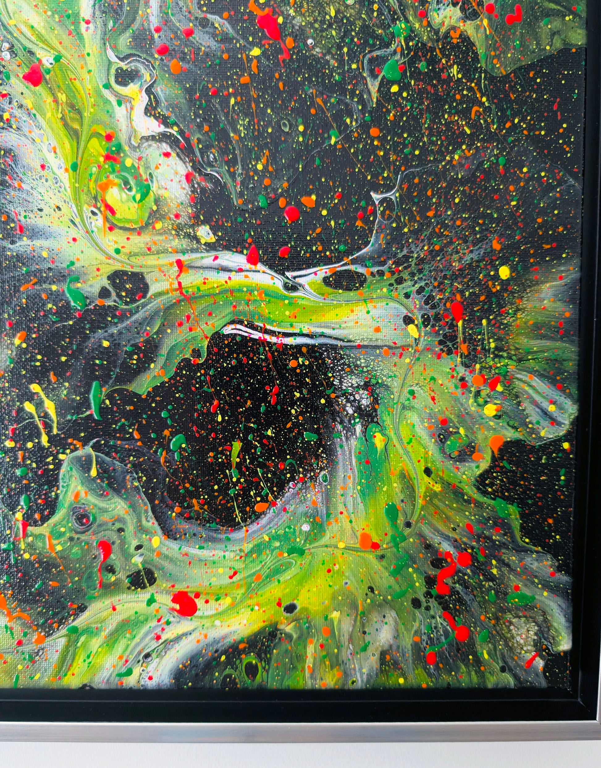 Detailed view of a neon green swirl meeting a deep black void, sprinkled with bright red, yellow, and orange paint splatters for a high-energy, cosmic effect.