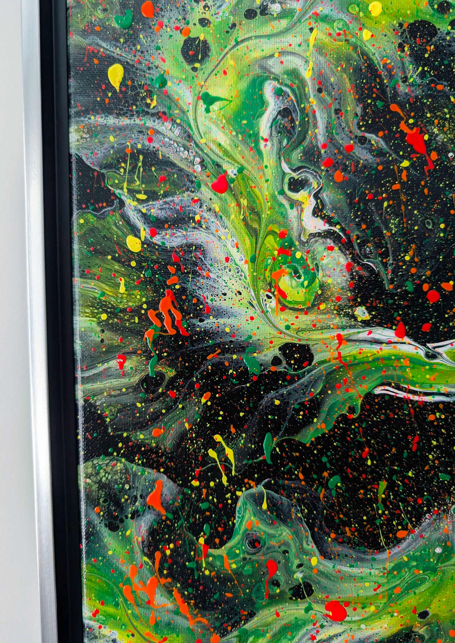 Zoomed-in section of the painting featuring a green and white swirl outlined by splashes of red and yellow. Tiny speckles fill the black space, creating a galaxy-like texture.