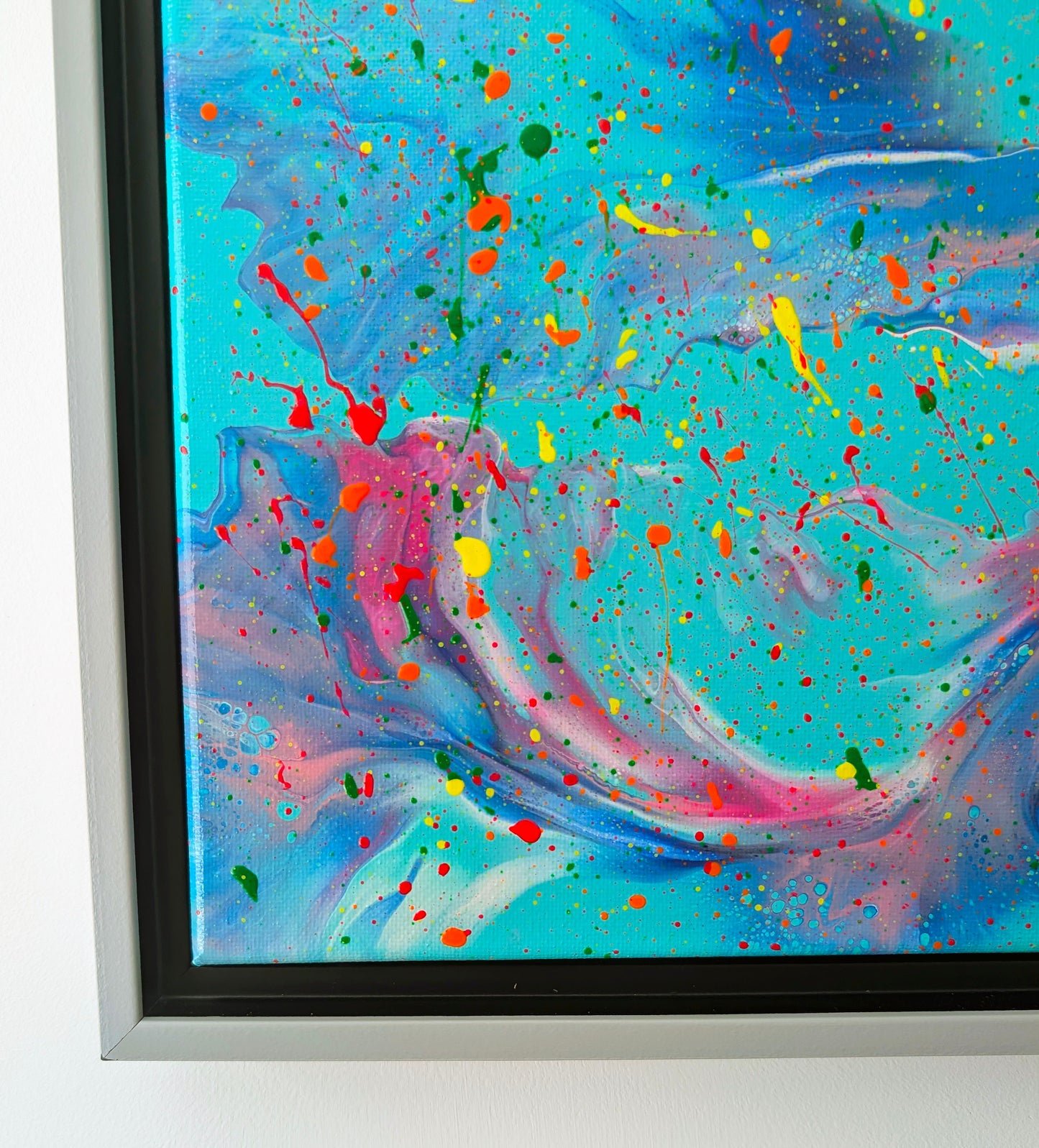 Detail of the bottom left corner, highlighting soft ribbons of pink, lavender, and blue against turquoise, interspersed with small multicolor specks and larger neon drips.